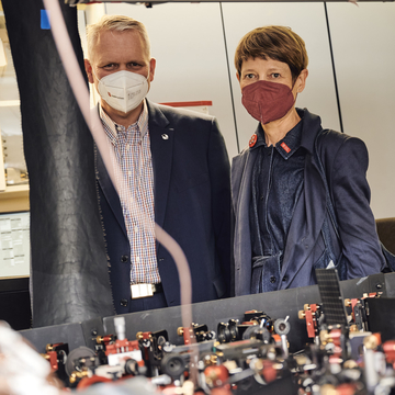 Minister Björn Thümler und Angela Ittel, Präsidentin der TU Braunschweig, stehen nebeneinander und betrachten Quantentechnologie.