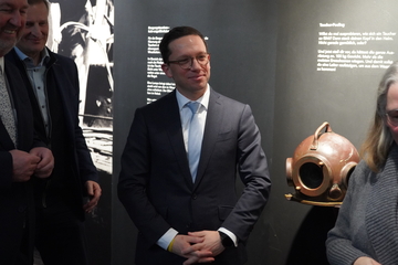 Niedersachsens Minister für Wissenschaft und Kultur Falko Mohrs steht beim Besuch im Museum Windstärke 10 in Cuxhaven neben einem Taucherhelm.