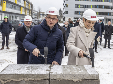 Minister Falko Mohrs legt zusammen mit TU-Präsidentin Prof. Angela Ittel den Grundstein des Physik-Neubaus. Beide tragen Harthelme, es hat auf der Baustelle geschneit.
