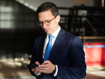 Minister Falko Mohrs schaut konzentriert lächelnd auf sein Smartphone.