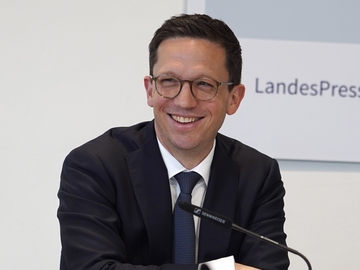 Minister Mohrs lächelt breit bei einer Pressekonferenz im niedersächsischen Landtag.