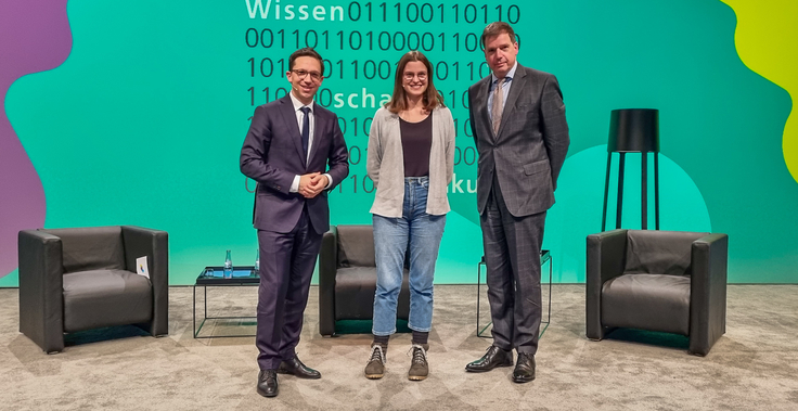 Drei Personen auf einer Bühne: Minister Falko Mohrs, Jana Mestmäcker, Dr. Thomas Richter (von links nach rechts).