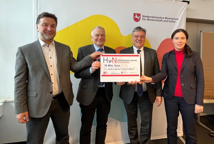 Michael Brinkwerth (TU Clausthal), Dr. Burkart Franz (TiHo), Prof. Dr. Joachim Schachtner (Staatssekretär für Wissenschaft und Kultur), Krystyna Redeker-Weißer (Koordinierungsstelle Hochschule.digital Niedersachsen) halten einen symbolischen Scheck.