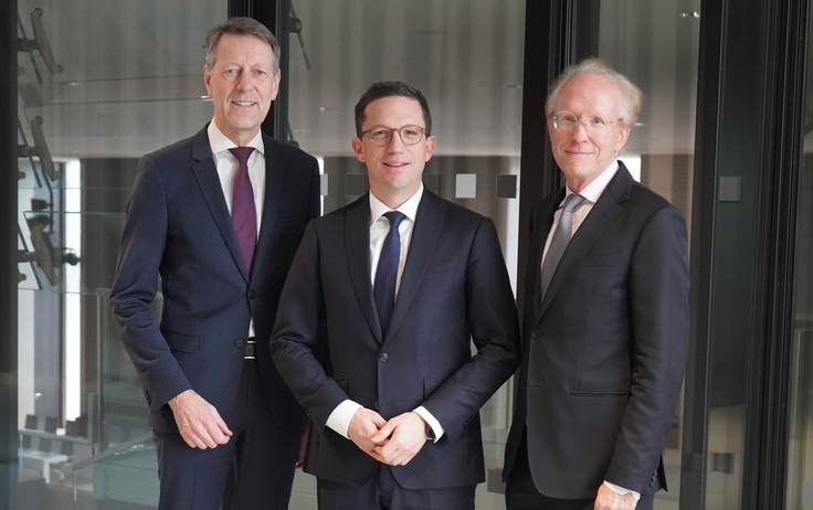 Stiftungsvorstand Dr. Georg Schütte, Wissenschaftsminister Falko Mohrs und Leuphana-Präsident Prof. Dr. Sascha Spoun stehen im Landtag vor einer gläsernen Tür.