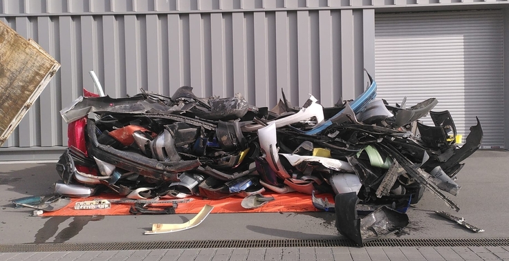 Ein Haufen Stoßstangen auf einem Betriebshof.