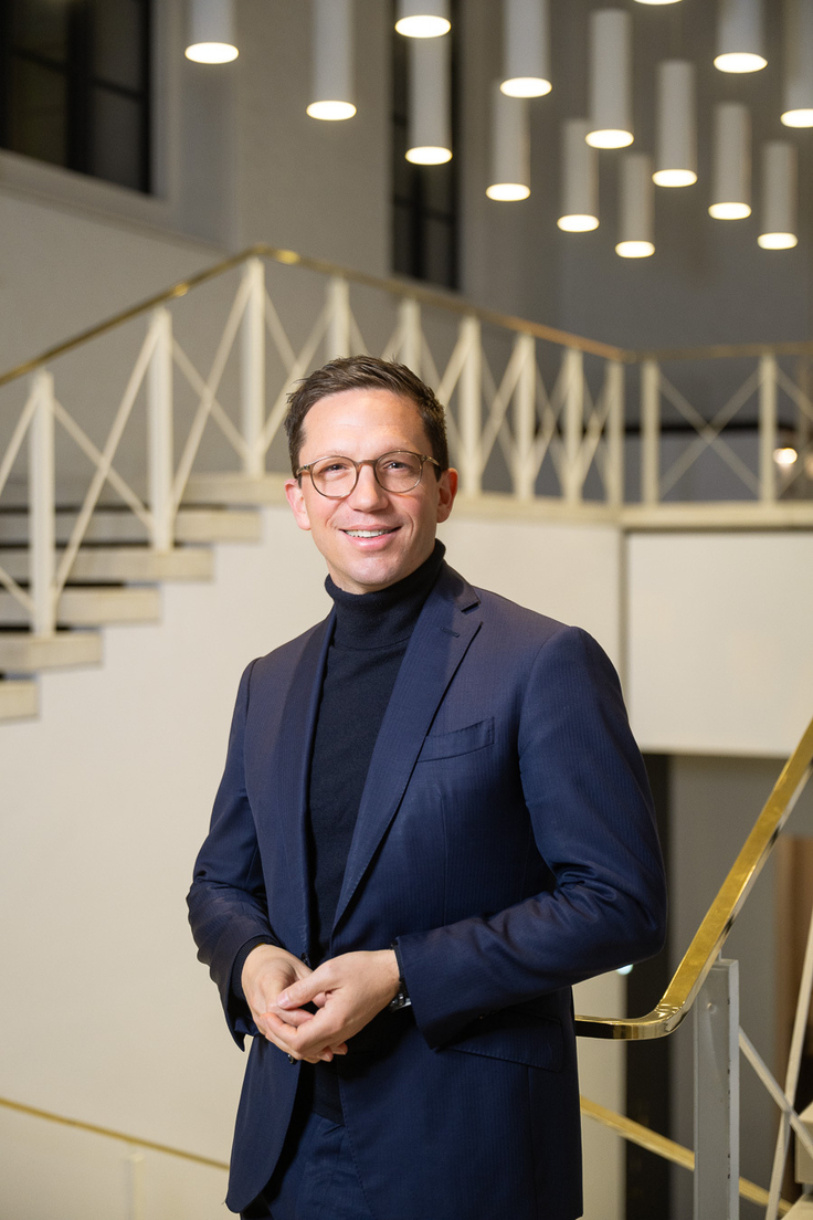 Minister Falko Mohrs steht in einem casual Sakko und Rollkragenpullover vor der Treppe des Schauspiels Hannover.