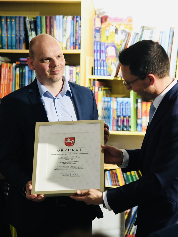 Minister Mohrs übergibt die Urkunde zum Buchhandelspreis 2026 an Herrn Patz, Inhaber des Buchladens Patz