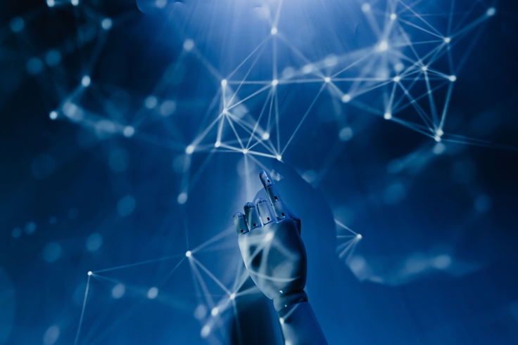 Symbolbild für digitale Vernetzung und Künstliche Intelligenz: Eine robotische Hand streckt den Zeigefinger zu einem Netzwerk aus leuchtenden Punkten und verbundenen Linien aus. Blaue Lichttöne, abstrakte Datenstrukturen prägen das Bild.