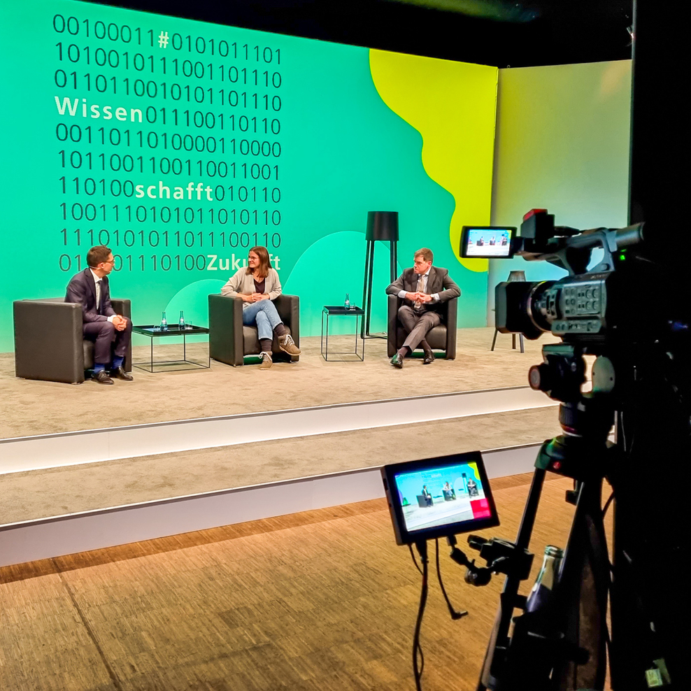 Drei Personen auf einer Bühne: Minister Falko Mohrs, Jana Mestmäcker, Dr. Thomas Richter (von links nach rechts).