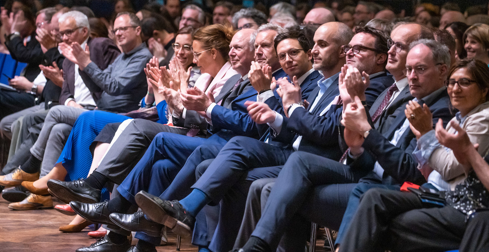Schmuckbild: Minister Falko Mohrs sitzt in der ersten Reihe eines Publikums, alle klatschen.