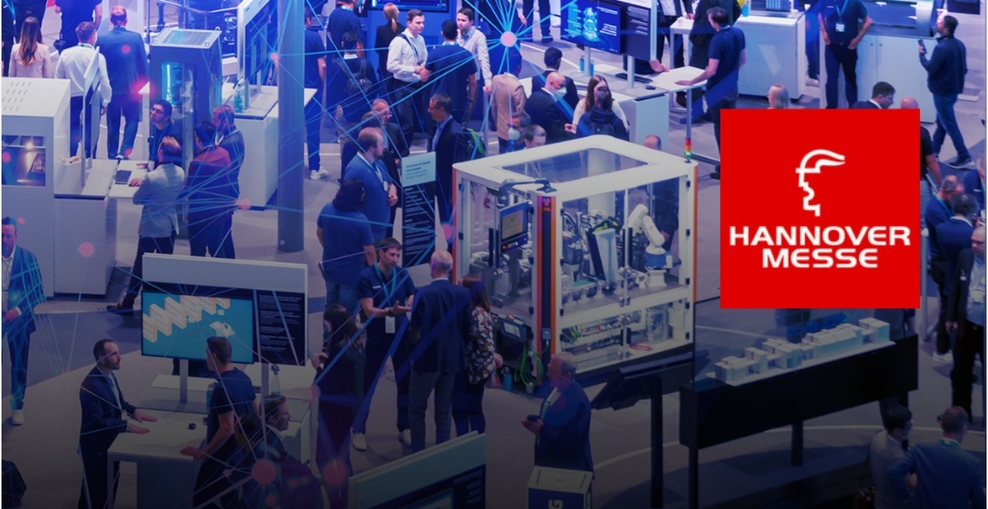 Schmuckbild: Das rote Hannover-Messe-Logo ist vor einem blauen Hintergrund zu sehen. Das Hintergrundbild zeigt Besuchende an den Messeständen, sie sind klein und nicht im Detail zu erkennen.