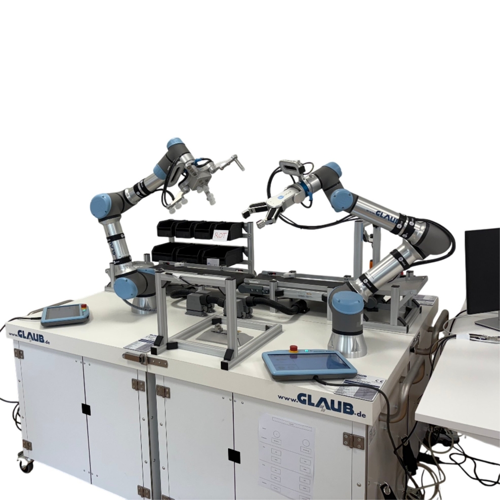 Die Abbildung zeigt zwei Roboterarme mit Greifhänden auf einem grauen Tisch.