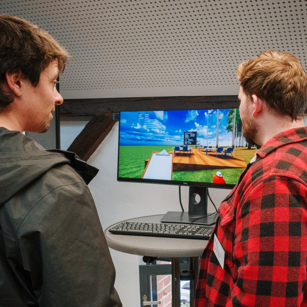 Zwei junge Männer besprechen eine Simulation auf einem Bildschirm.