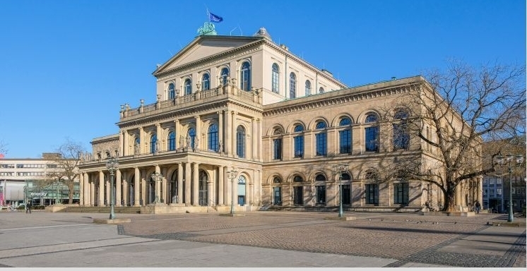 Die Staatsoper Hannover an einem sonnigen Tag vor einem klaren, wolkenlosen blauen Himmel.