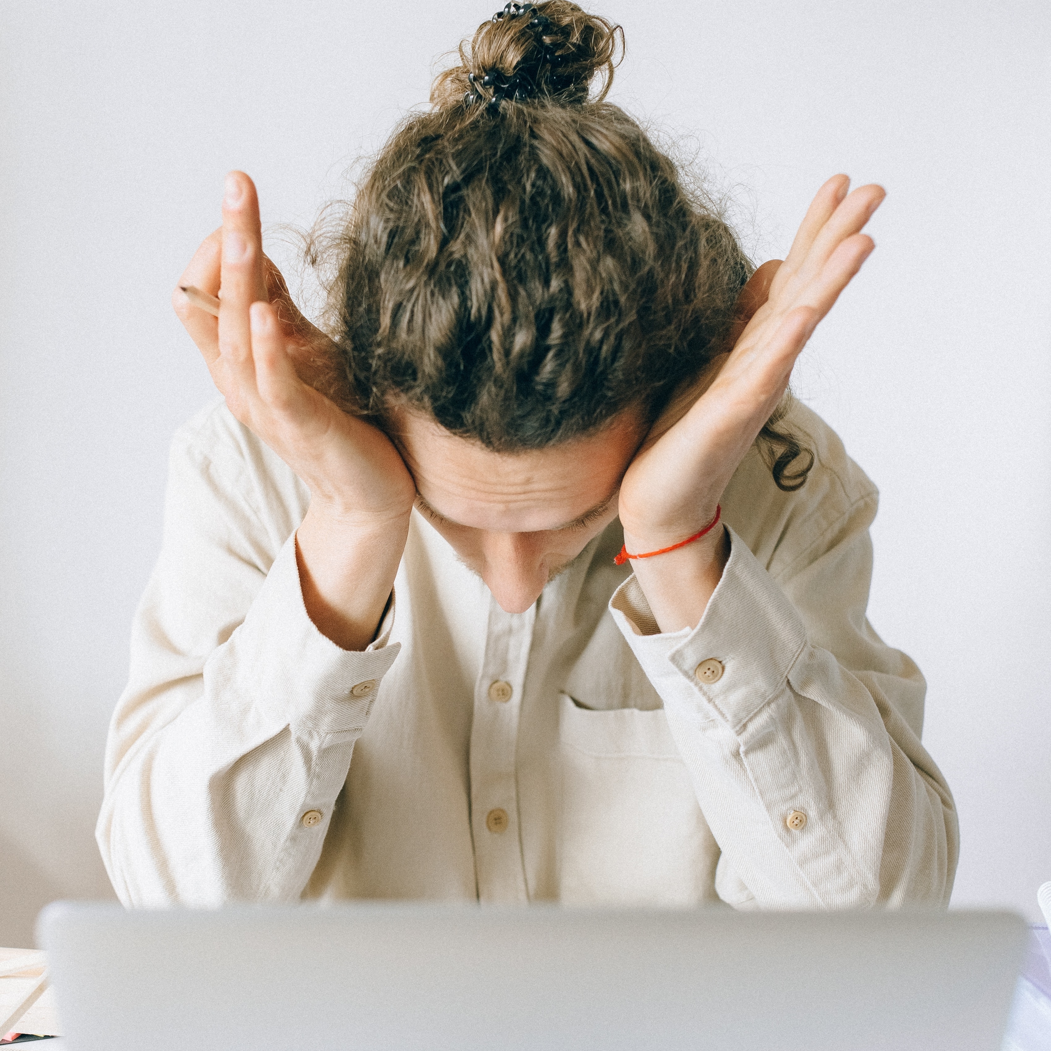 Schmuckbild: Eine Person sitzt vor einem Laptop und stützt den Kopf auf die Hände.