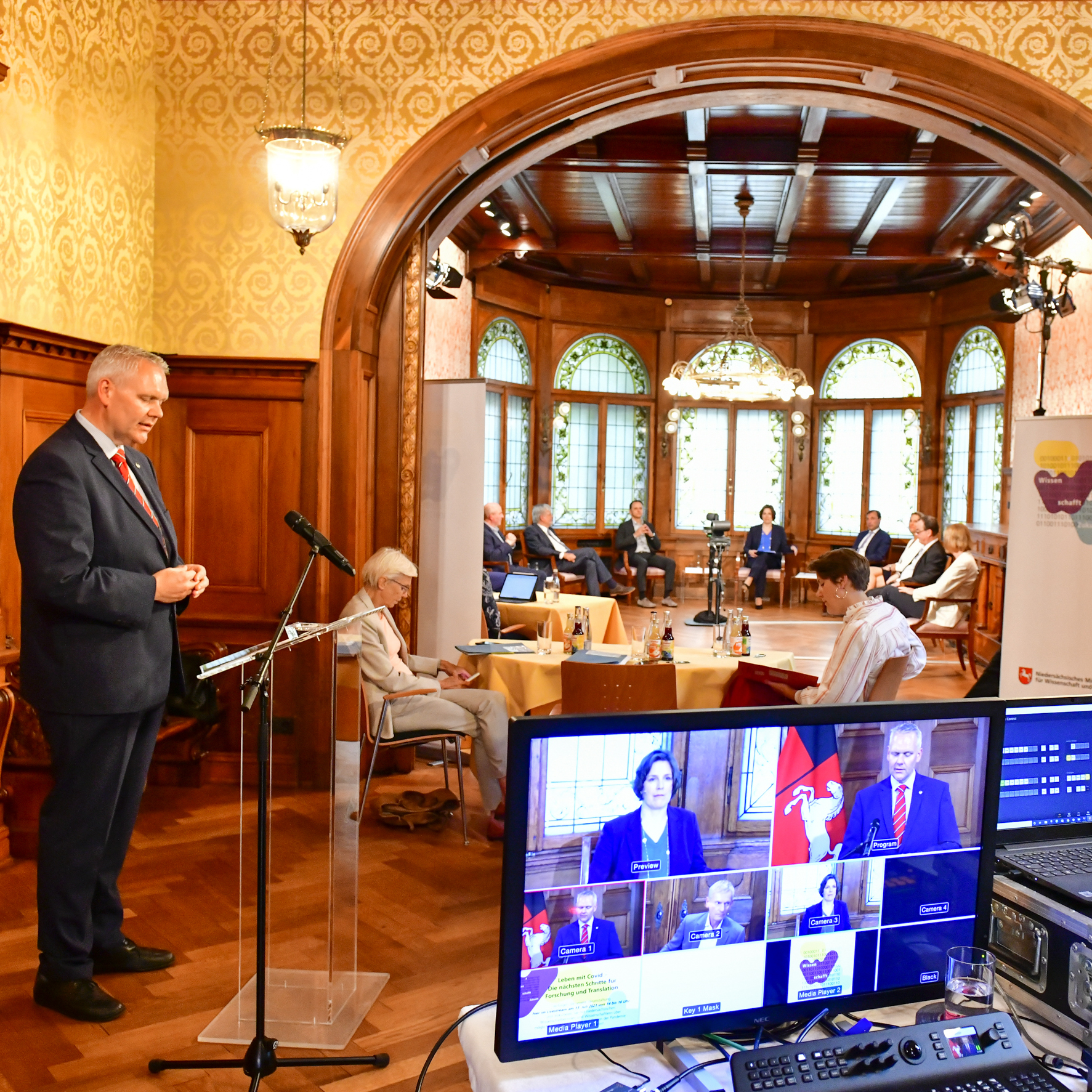 Blick in die Halle des Gästehauses der Niedersächsischen Landesregierung, in der gerade eine Podiumsdiskussion live gestreamt wird. Links steht Minister Björn Thümler.